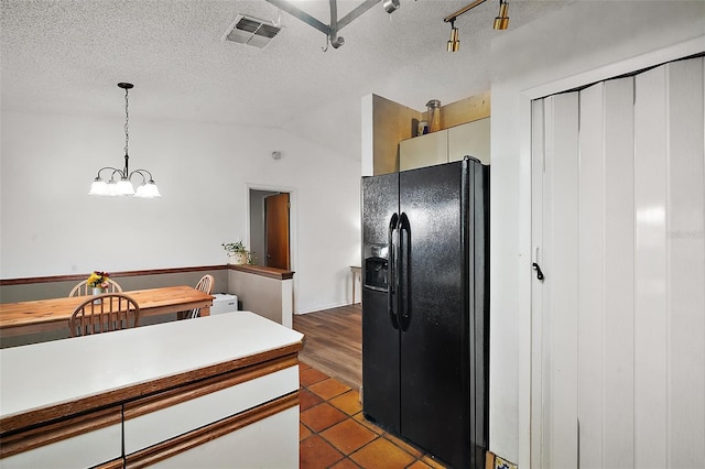 kitchen featuring lofted ceiling, visible vents, hanging light fixtures, black fridge with ice dispenser, and a textured ceiling