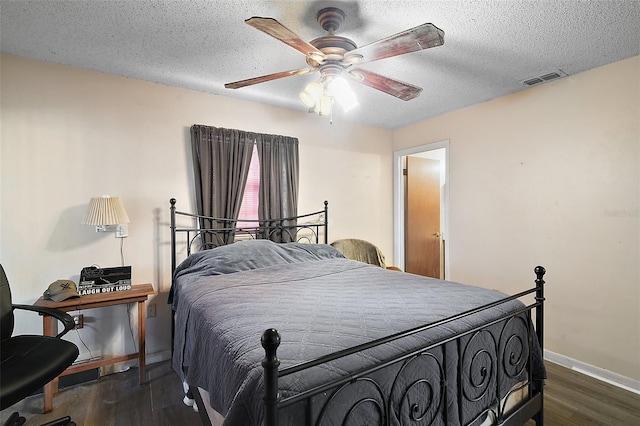 bedroom with baseboards, visible vents, a ceiling fan, wood finished floors, and a textured ceiling