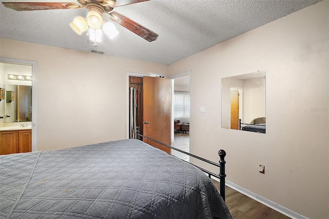 bedroom featuring visible vents, a ceiling fan, wood finished floors, ensuite bathroom, and a textured ceiling