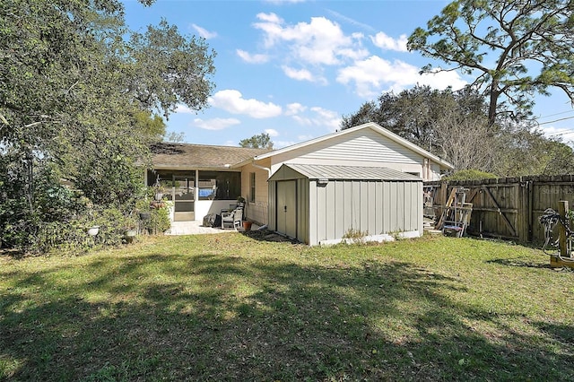 rear view of house featuring a storage shed, a fenced backyard, an outbuilding, and a yard