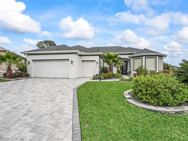 view of front of home featuring a garage, a shingled roof, decorative driveway, stucco siding, and a front lawn