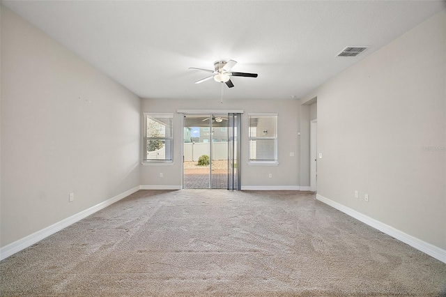 carpeted spare room with a ceiling fan, visible vents, and baseboards