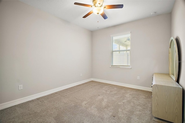 carpeted empty room with baseboards and a ceiling fan