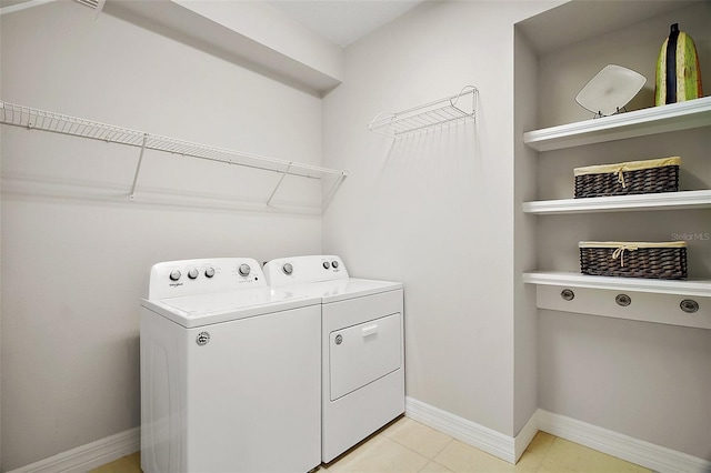 laundry area with laundry area, washing machine and dryer, light tile patterned floors, and baseboards