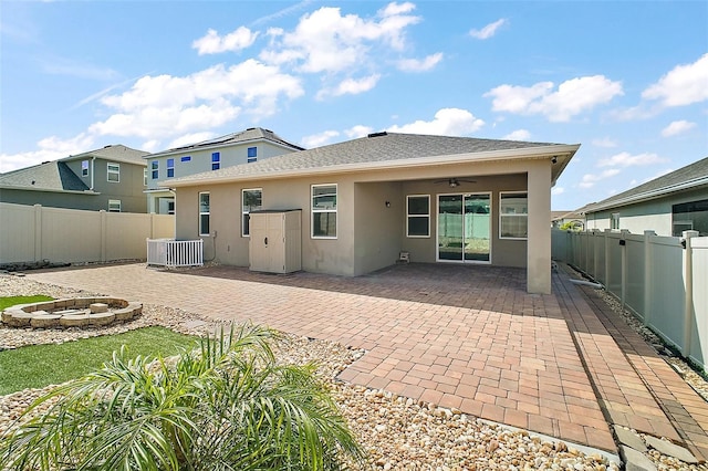 back of property with stucco siding, a ceiling fan, an outdoor fire pit, cooling unit, and a fenced backyard