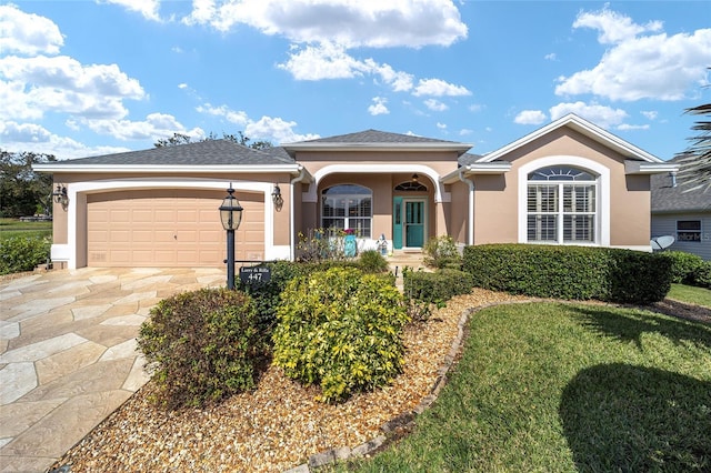 ranch-style house featuring driveway, an attached garage, a front lawn, and stucco siding