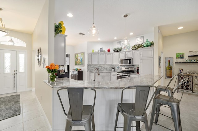 kitchen featuring appliances with stainless steel finishes, backsplash, a peninsula, and light stone countertops