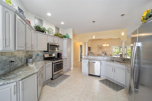 kitchen featuring a sink, appliances with stainless steel finishes, tasteful backsplash, decorative light fixtures, and ornate columns