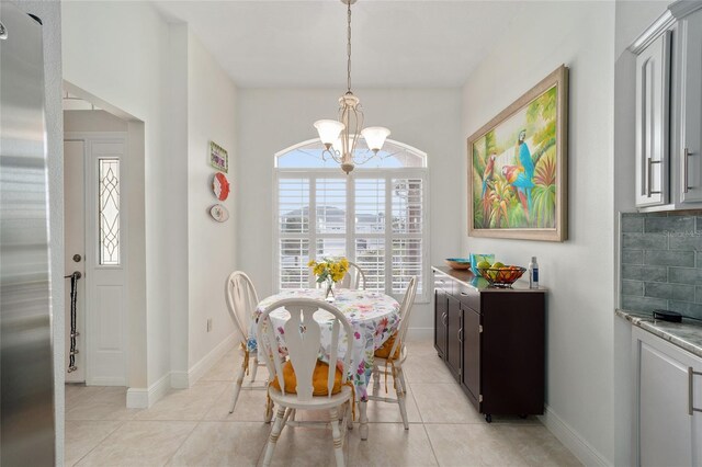 dining area with light tile patterned floors, baseboards, and a chandelier