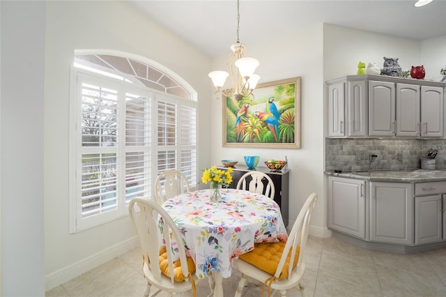 dining space featuring light tile patterned floors, baseboards, and an inviting chandelier