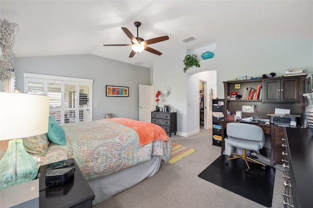 bedroom featuring light carpet, arched walkways, visible vents, lofted ceiling, and a spacious closet