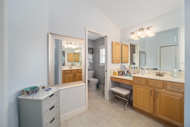 bathroom with toilet, two vanities, a sink, vaulted ceiling, and tile patterned floors