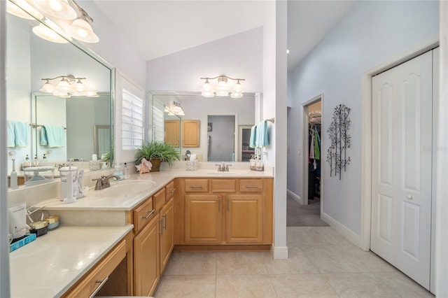 bathroom with vaulted ceiling, double vanity, tile patterned flooring, and a sink