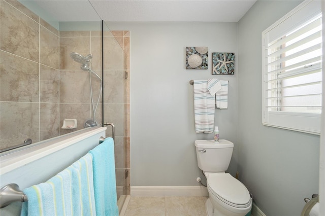 bathroom with tile patterned flooring, baseboards, a tile shower, and a wealth of natural light