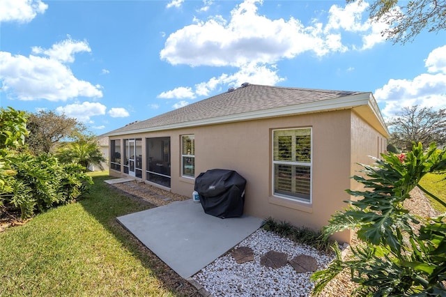 back of property featuring a sunroom, roof with shingles, a yard, a patio area, and stucco siding