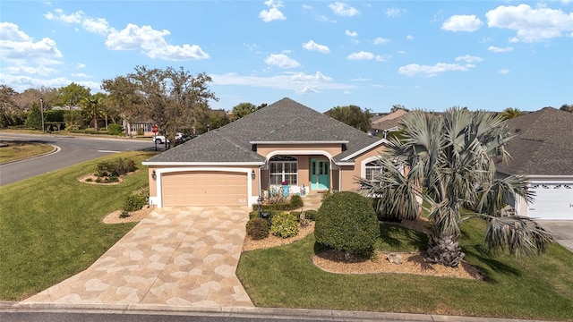 view of front facade with driveway, a shingled roof, an attached garage, a front lawn, and stucco siding