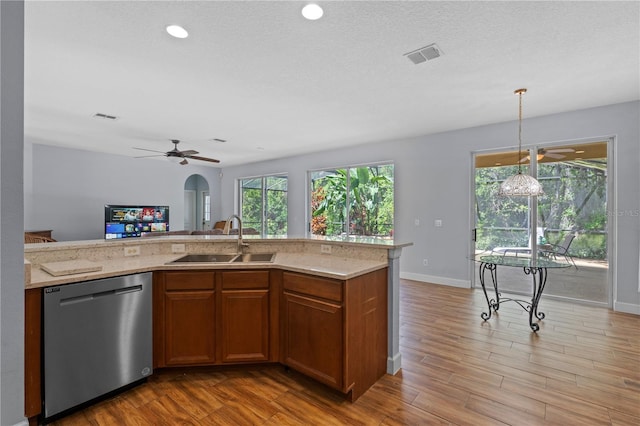 3430 Turningwind Ln, Winter Garden, FL 34787 - kitchen with stainless steel dishwasher, a sink, ceiling fan, brown cabinets, and light wood-style flooring