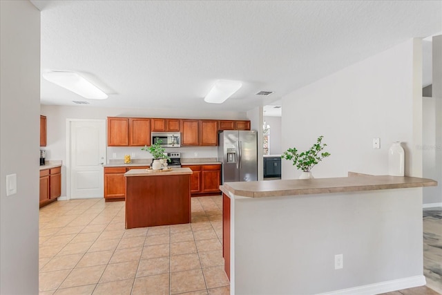 kitchen with a textured ceiling, stainless steel appliances, light tile patterned flooring, and light countertops