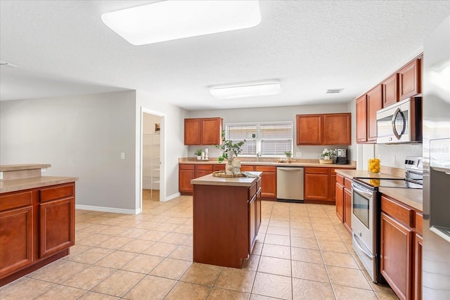 kitchen featuring a textured ceiling, stainless steel appliances, visible vents, light countertops, and a center island