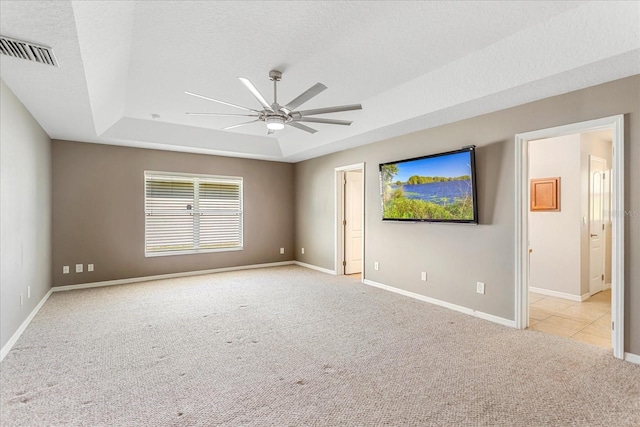 unfurnished room featuring carpet, visible vents, a tray ceiling, and a textured ceiling