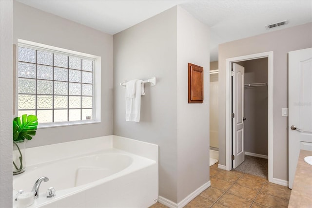 bathroom with visible vents, a bath, tile patterned floors, a stall shower, and a walk in closet