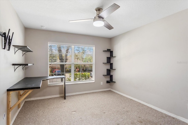 unfurnished office with a textured ceiling, carpet, a ceiling fan, and baseboards