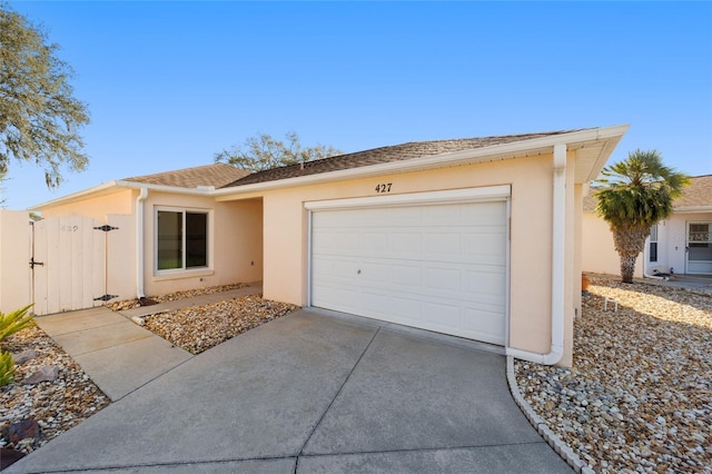 ranch-style home with stucco siding, a garage, driveway, and a gate