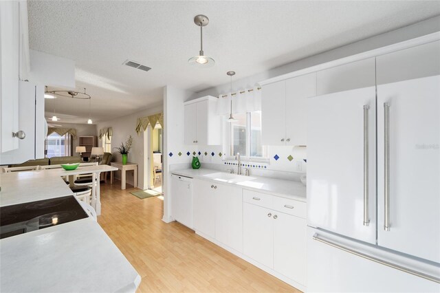 kitchen with visible vents, high end white fridge, a sink, hanging light fixtures, and light countertops