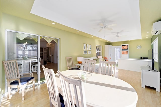 dining room featuring a wall mounted air conditioner, a ceiling fan, recessed lighting, light wood-style floors, and a raised ceiling