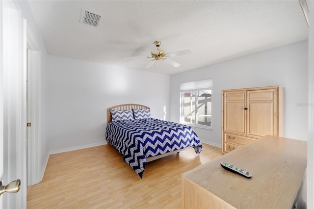 bedroom with visible vents, a textured ceiling, baseboards, and light wood-style floors