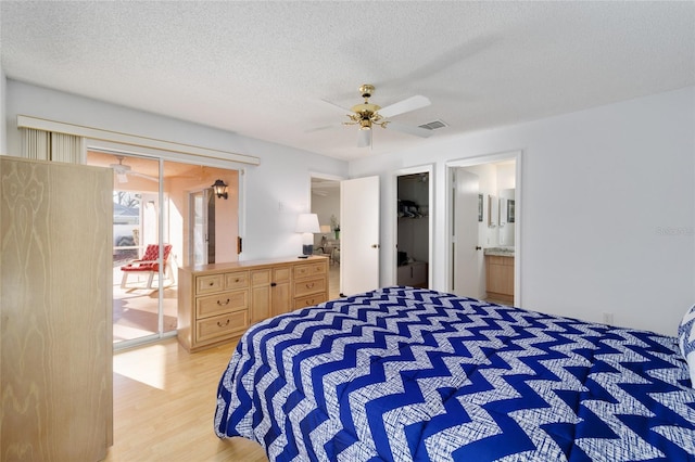 bedroom featuring a spacious closet, visible vents, light wood-style floors, a closet, and a textured ceiling