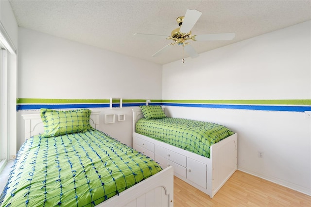 bedroom featuring ceiling fan, light wood-type flooring, and a textured ceiling