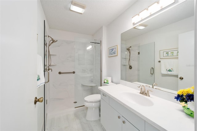 bathroom featuring vanity, wood finished floors, a stall shower, a textured ceiling, and toilet