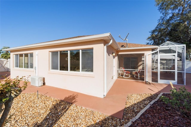 rear view of house with ac unit, stucco siding, a patio, and a lanai