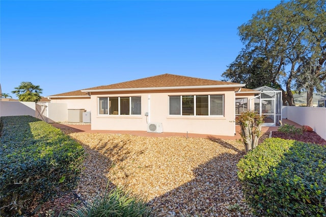 rear view of house with a lanai, stucco siding, a fenced backyard, and roof with shingles