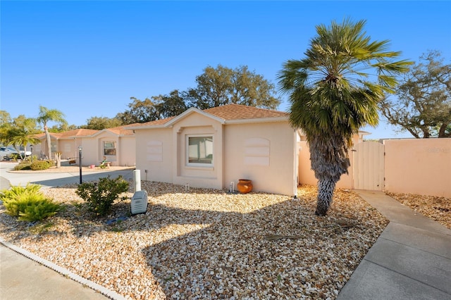 view of side of home featuring stucco siding and a gate