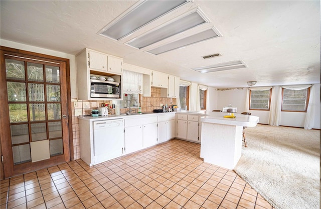 kitchen with a healthy amount of sunlight, dishwasher, light countertops, and a peninsula