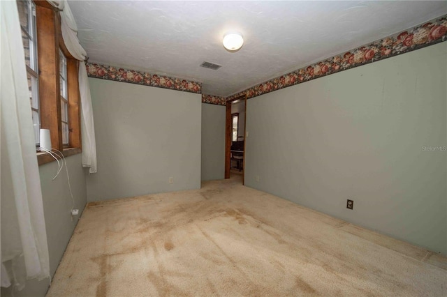 carpeted empty room featuring visible vents and a textured ceiling