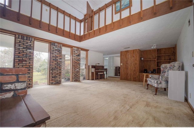 carpeted living room with wood walls and a high ceiling