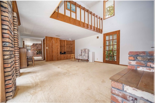 unfurnished living room with a high ceiling, carpet flooring, a healthy amount of sunlight, and baseboards