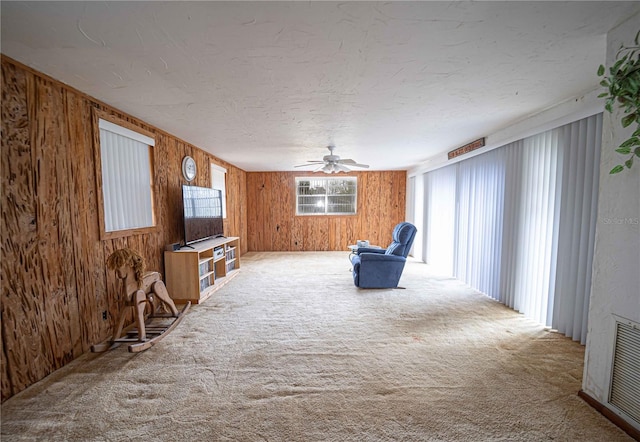 unfurnished room with visible vents, carpet floors, wooden walls, and a textured ceiling