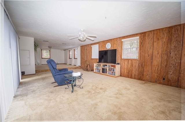 unfurnished living room with wooden walls, a textured ceiling, a ceiling fan, and carpet