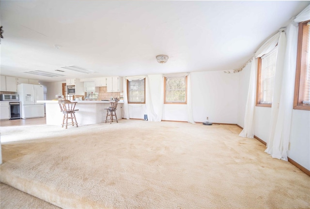 unfurnished living room with baseboards and light carpet