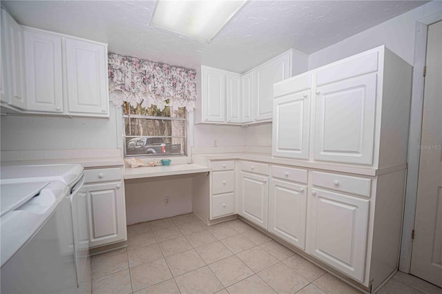 kitchen with light tile patterned floors, separate washer and dryer, light countertops, white cabinets, and built in desk