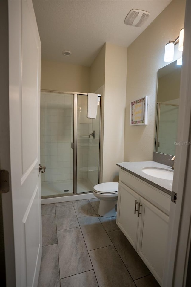 bathroom featuring toilet, a shower stall, visible vents, and vanity