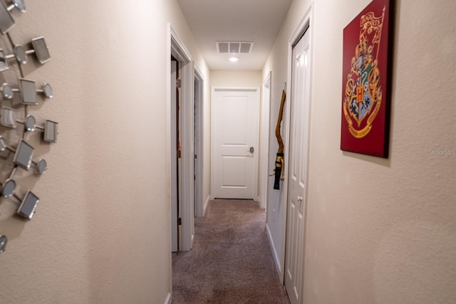 hallway featuring carpet, visible vents, and baseboards