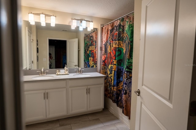 full bath featuring a textured ceiling, double vanity, a sink, and tile patterned floors