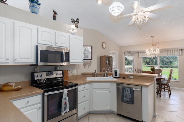 kitchen featuring white cabinets, appliances with stainless steel finishes, a peninsula, vaulted ceiling, and a sink