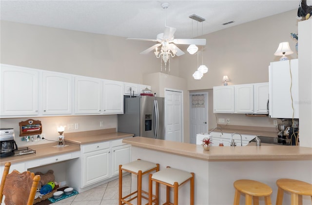 kitchen featuring a kitchen bar, stainless steel fridge, and white cabinetry