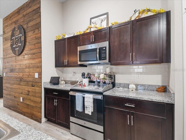 kitchen with stainless steel appliances, light stone counters, backsplash, and dark brown cabinets